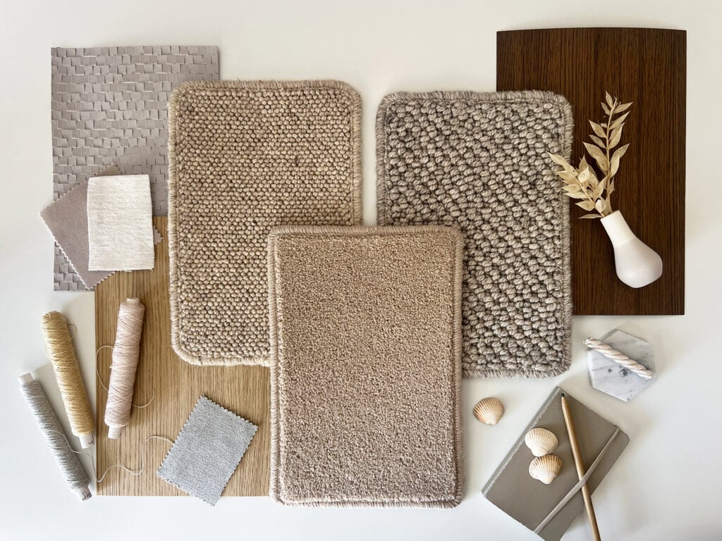 Flatlay of carpet swatches, fabric samples, and decor accents in beige, taupe, and grey tones showcasing neutral home trends.