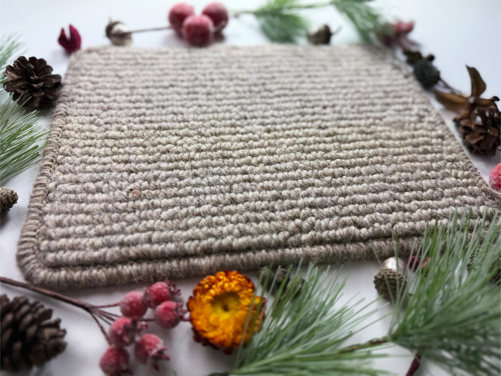 Neutral woven carpet sample styled with pine cones, foliage and autumnal décor, natural home décor flooring inspiration.
