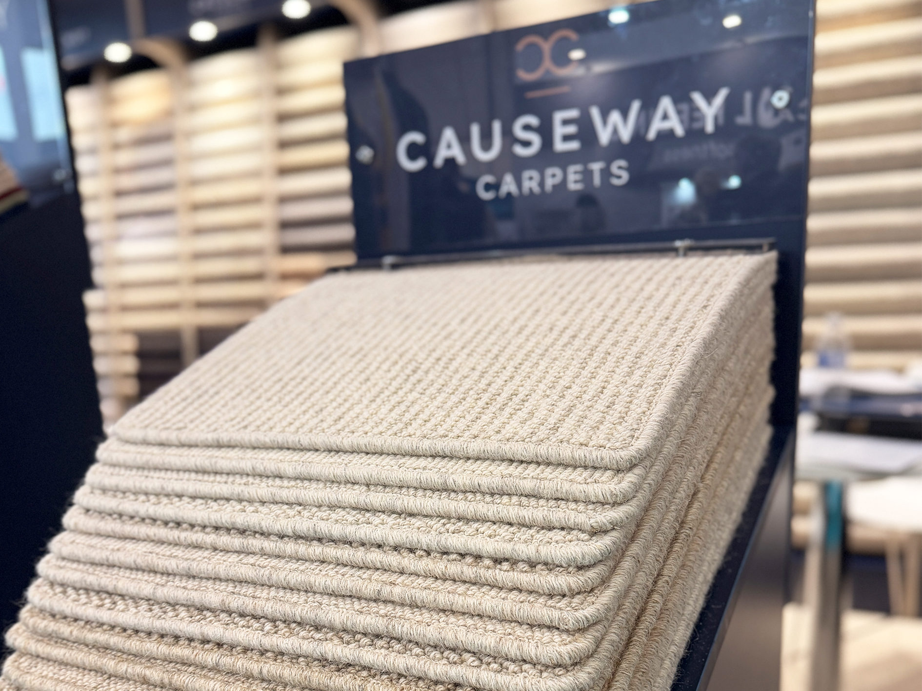 Close-up of stacked beige carpet swatches on a Causeway Carpets display.