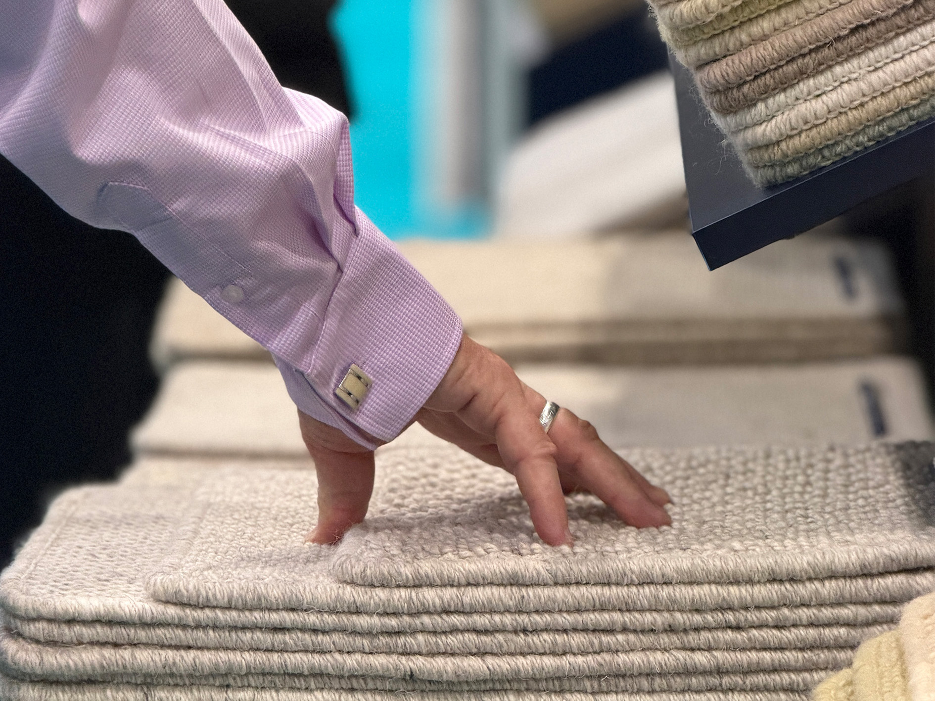 Close-up of a textured wool carpet sample being examined at The Flooring Show, showcasing the quality and craftsmanship of Causeway Carpets.